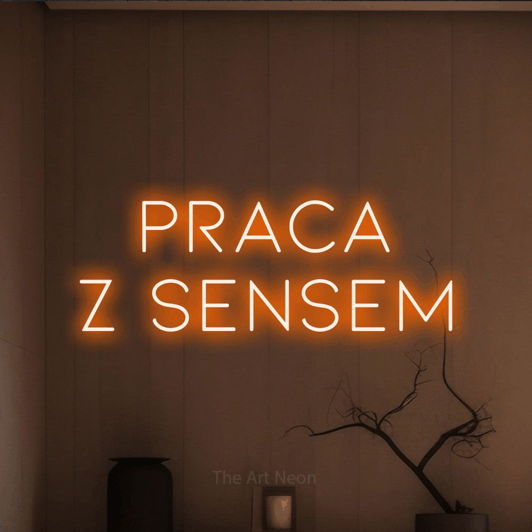 LED neon sign reading “PRACA Z SENSEM”, arranged in two lines.