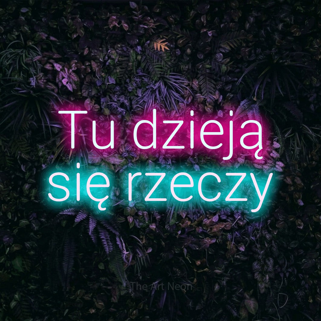LED neon sign reading “Tu dzieją się rzeczy”, arranged in two lines.