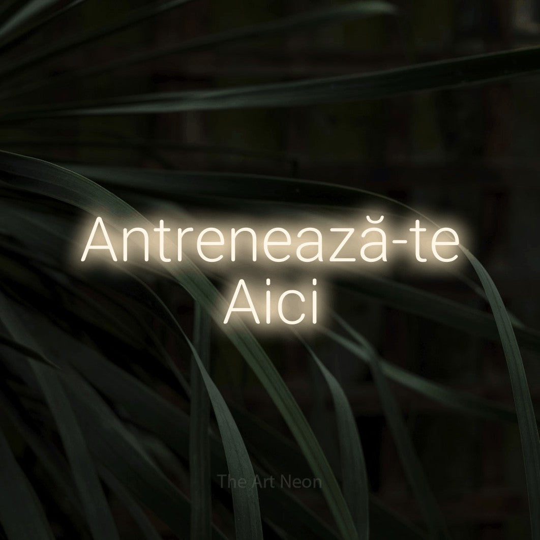 LED neon sign reading “Antrenează-te Aici”, arranged in two lines.