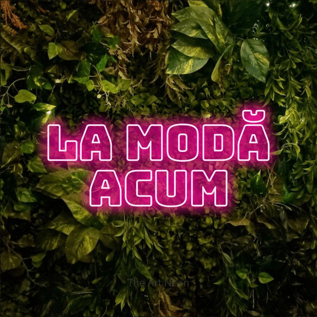 LED neon sign reading “La Modă Acum”, arranged in two lines.
