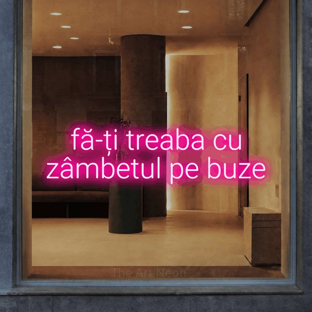 LED neon sign reading “fă-ți treaba cu zâmbetul pe buze”, arranged in two lines.
