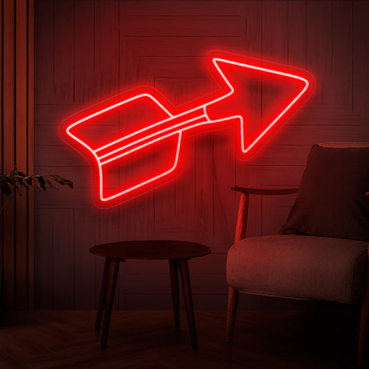 An illuminated neon sign featuring a vibrant red arrow, symbolizing direction and pointing towards a stylish and decorative element, adding a captivating focal point to any space.