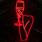 La imagen muestra un vibrante letrero de neón LED que representa la silueta de una mujer sosteniendo una copa de vino.
