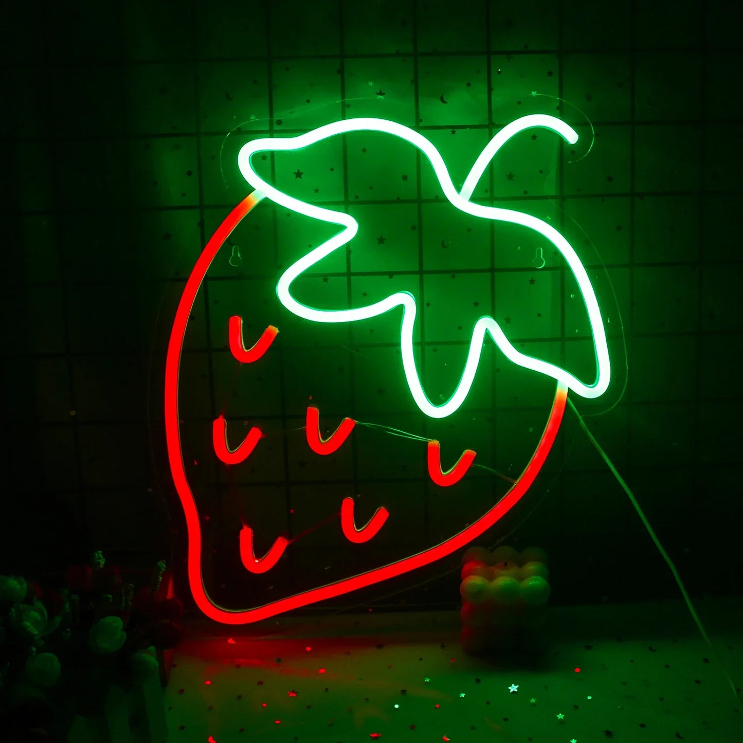 A vibrant LED neon sign in the shape of a strawberry, featuring a bright red body with lush green leaves on top.