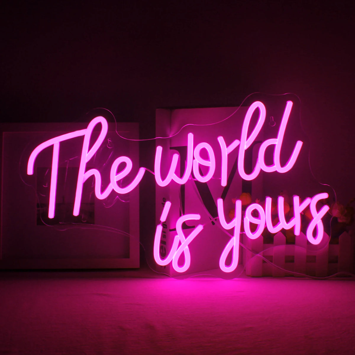 Et levende LED-neonskilt med ordene "The World Is Yours" i en stilfuld, kursiv skrifttype.