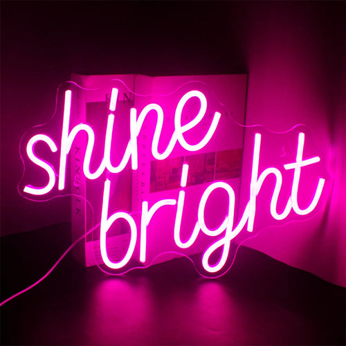 Imaginea prezintă o pancartă cu neon LED vibrantă și elegantă pe care scrie „Shine Bright” cu o scriere de mână elegantă, cursivă.