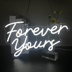 O panou cu neon LED vibrant care afișează expresia „Forever Yours” în litere cursive elegante.