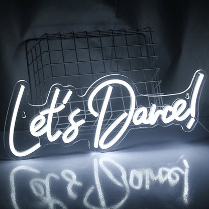 A brightly lit "Let's Dance" LED neon sign in vibrant pink and blue colors.