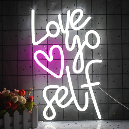 Obrázek zobrazuje zářivý neonový nápis LED se slovy „Love Yourself“ osvětleným stylovým písmem.