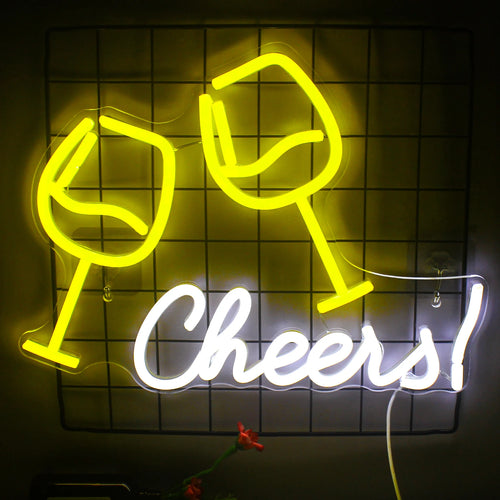 Una vivace insegna al neon a LED con la scritta "Cheers" scritta in un divertente carattere corsivo è montata contro un muro di mattoni.