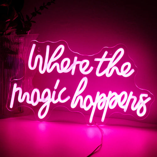 Imaginea prezintă un panou cu neon LED vibrant pe care scrie „Where The Magic Happens” într-un font elegant și jucăuș.