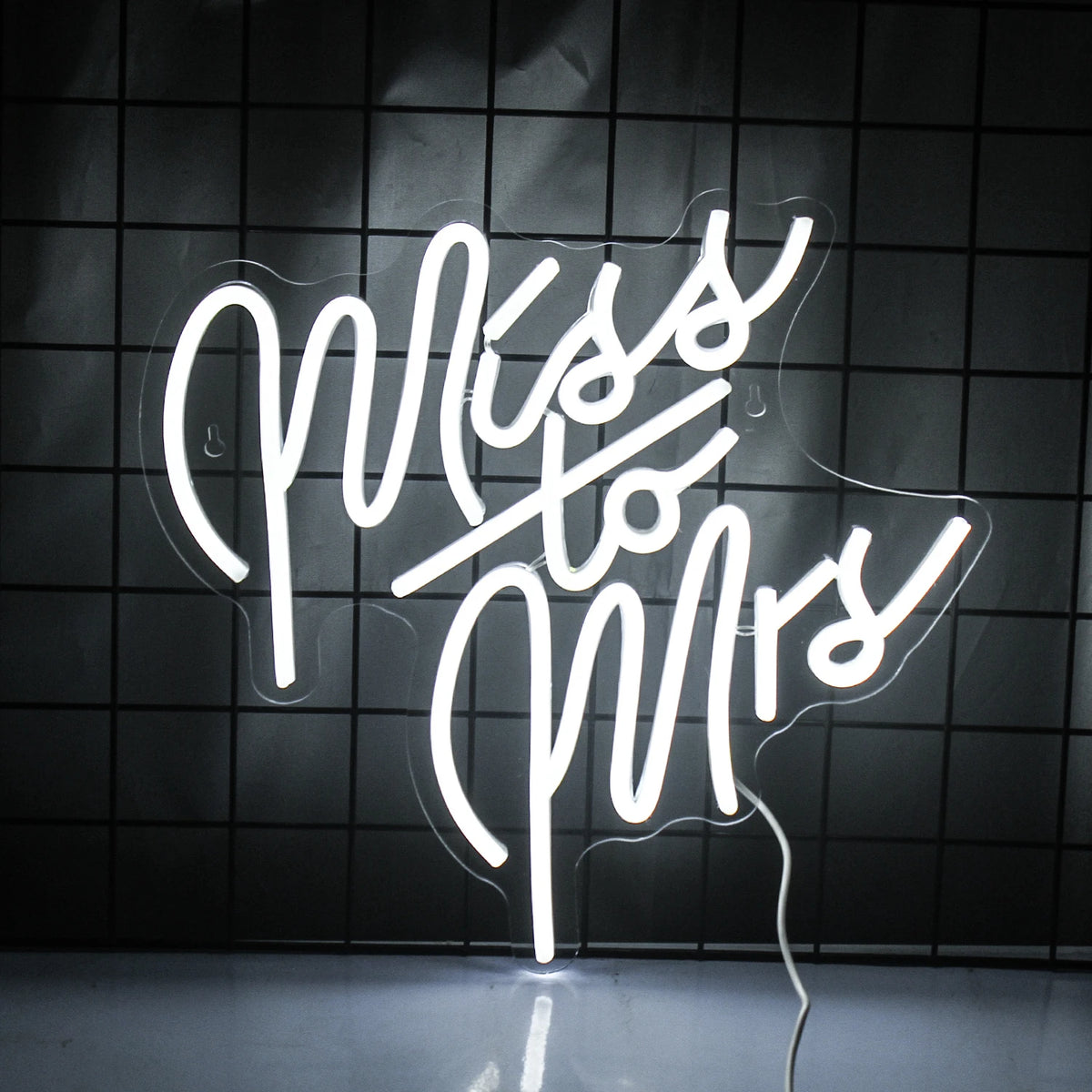 Na obrázku je stylový neonový LED nápis zobrazující slova „Miss To Mrs“ plynulým písmem.