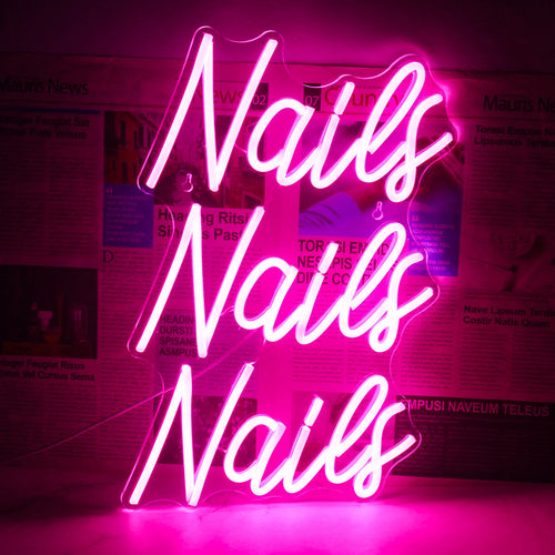 Na zdjęciu widoczny jest jaskrawy i przyciągający wzrok neon LED, na którym stylową, kursywną czcionką widnieje napis „Nails”.
