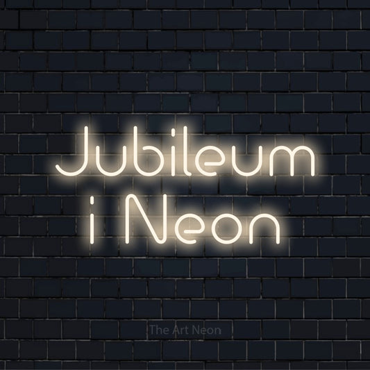Personlig neonskylt med texten “Jubileum i Neon” på en svart tegelvägg