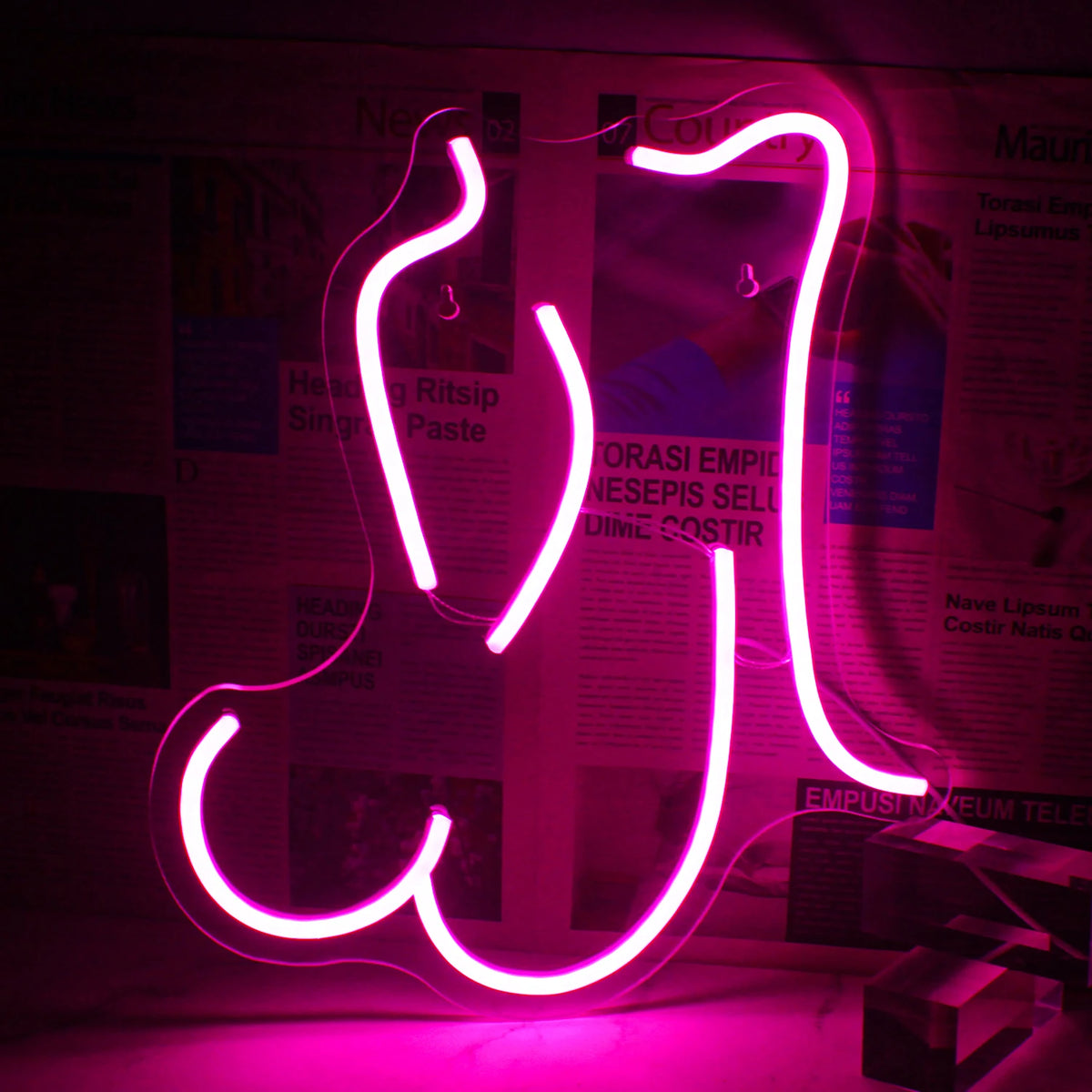 Une enseigne au néon LED rose vibrante en forme de contour stylisé d'une femme en position allongée.