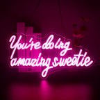 Un panneau néon LED vibrant affichant la phrase « You're Doing Amazing Sweetie » dans une écriture cursive élégante.