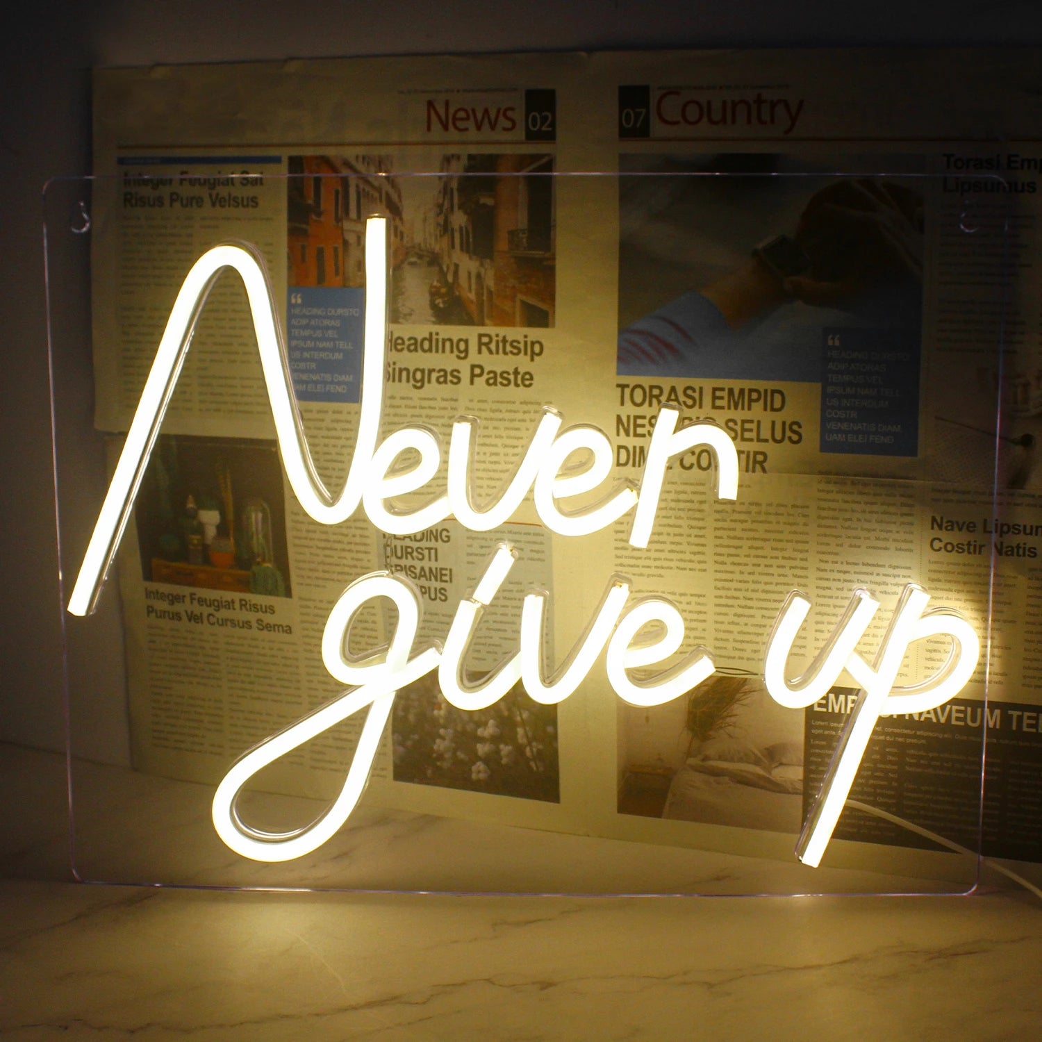 The image features a vibrant LED neon sign displaying the motivational phrase "Never Give Up" in bold, cursive lettering.