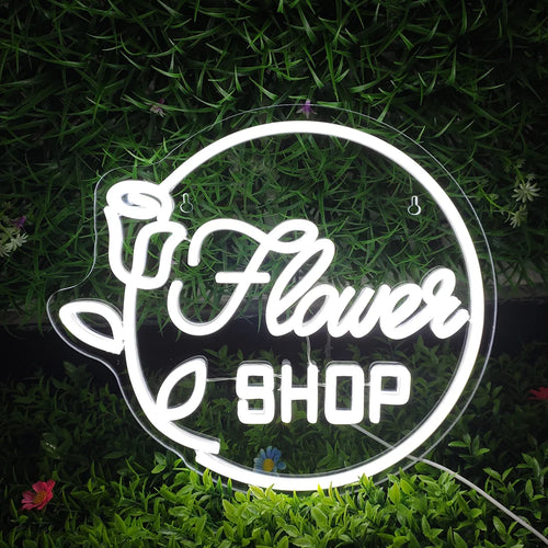 L'immagine presenta una vivace insegna al neon a LED con la scritta "Flower Shop" in un elegante carattere tipografico.