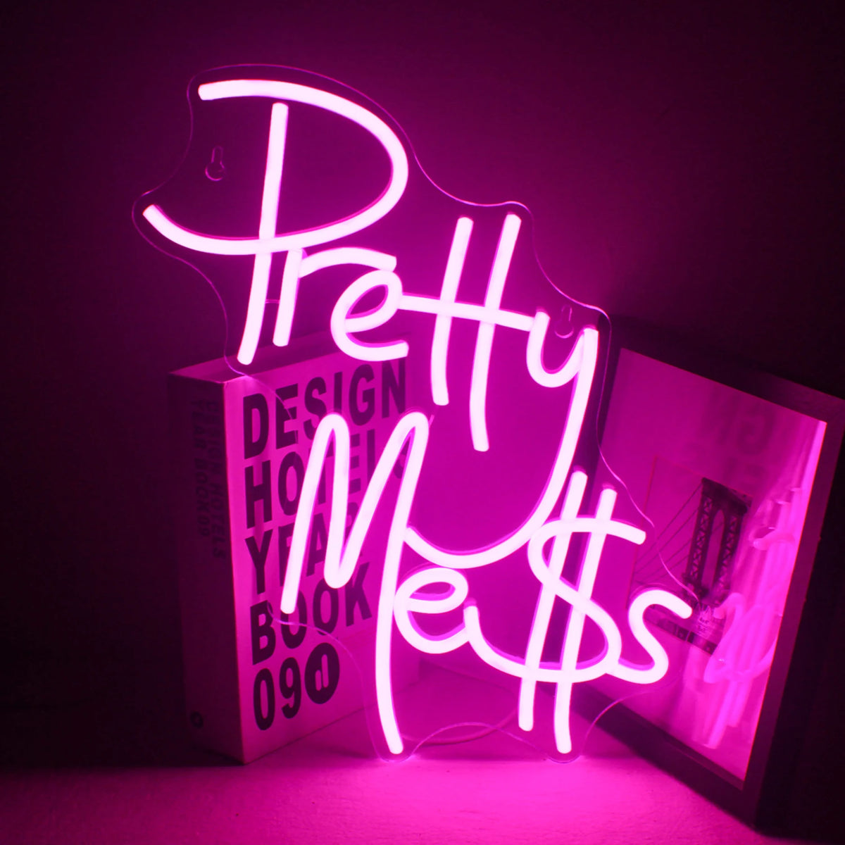 Na obrázku je zářivý, ručně vyrobený neonový nápis LED zobrazující slova „Pretty Mess“ elegantním kurzívou.