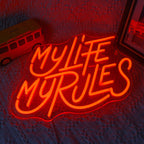 A vibrant LED neon sign displaying the words "My Life My Rules" in a lively cursive font.