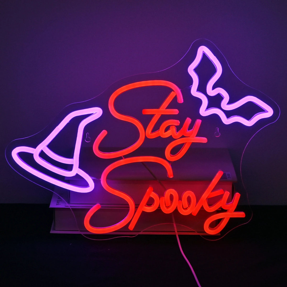 A képen egy kézzel készített LED fényreklám látható, amelyen a „Stay Spooky” felirat látható játékos, gördülékeny forgatókönyvben.