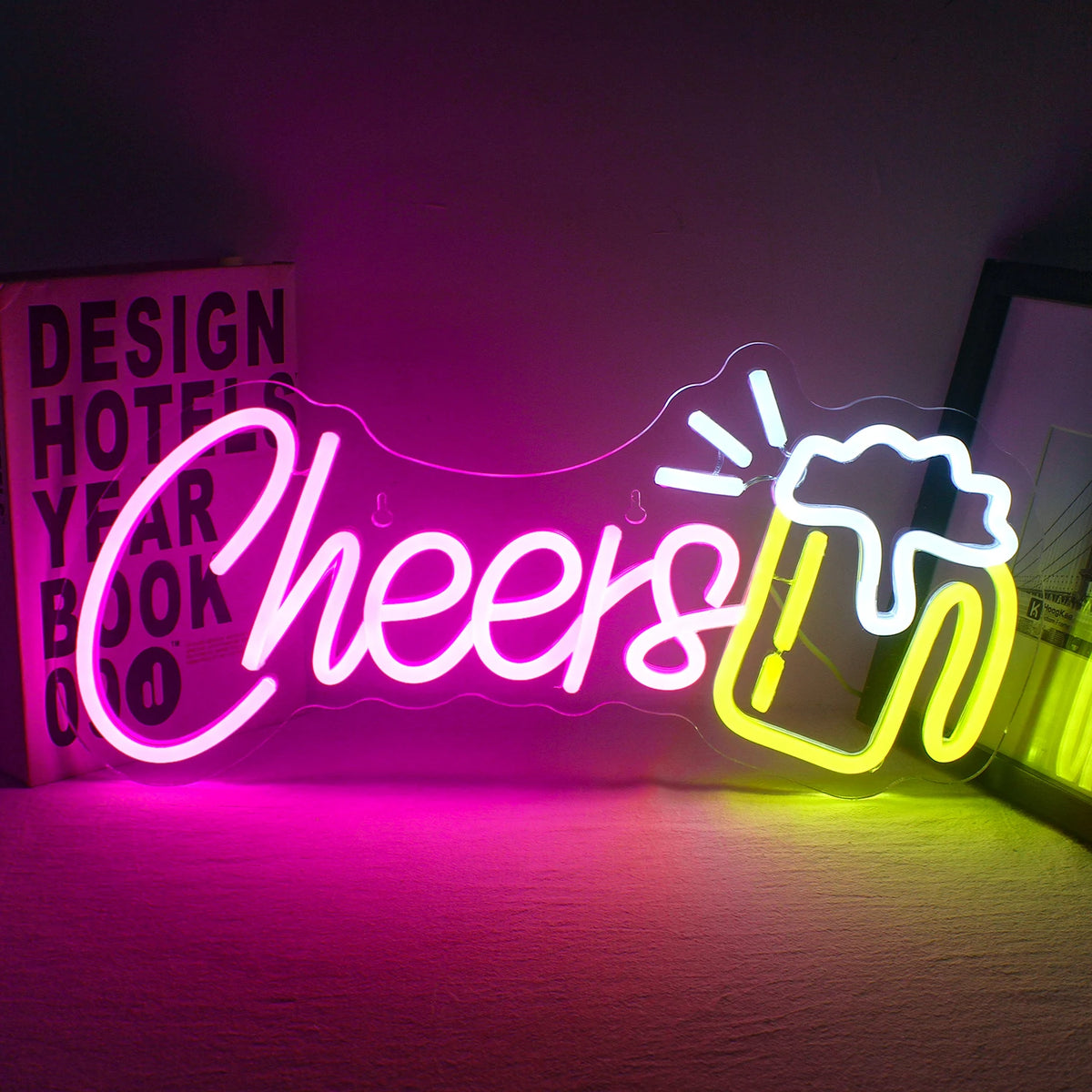 Das Bild zeigt ein leuchtendes „Cheers“-LED-Neonschild, das vor einem dunklen Hintergrund leuchtet.