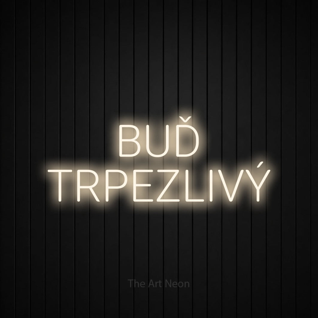 LED neon sign reading “BUĎ TRPEZLIVÝ”, arranged in two lines.