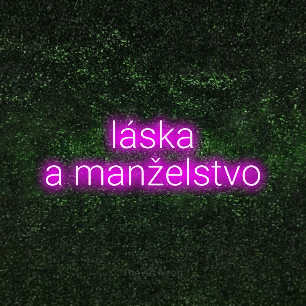 LED neon sign reading “láska a manželstvo”, arranged in two lines.