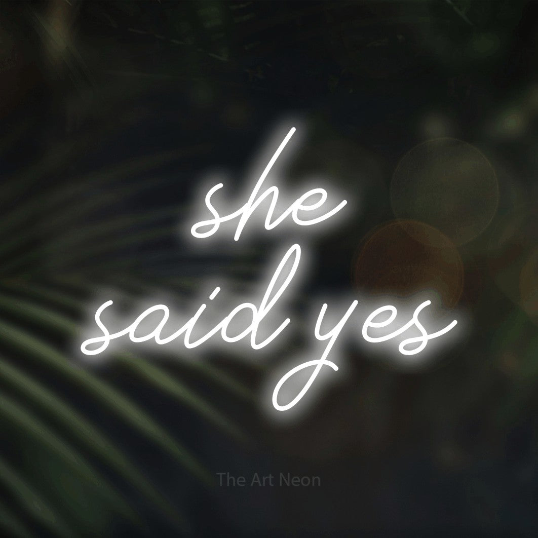 LED neon sign reading “she said yes”, arranged in two lines.