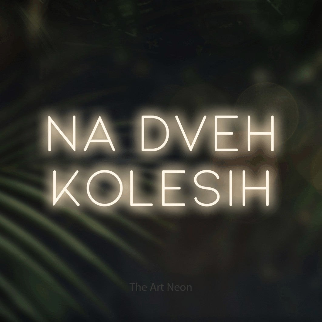 LED neon sign reading “na dveh kolesih”, arranged in two lines.