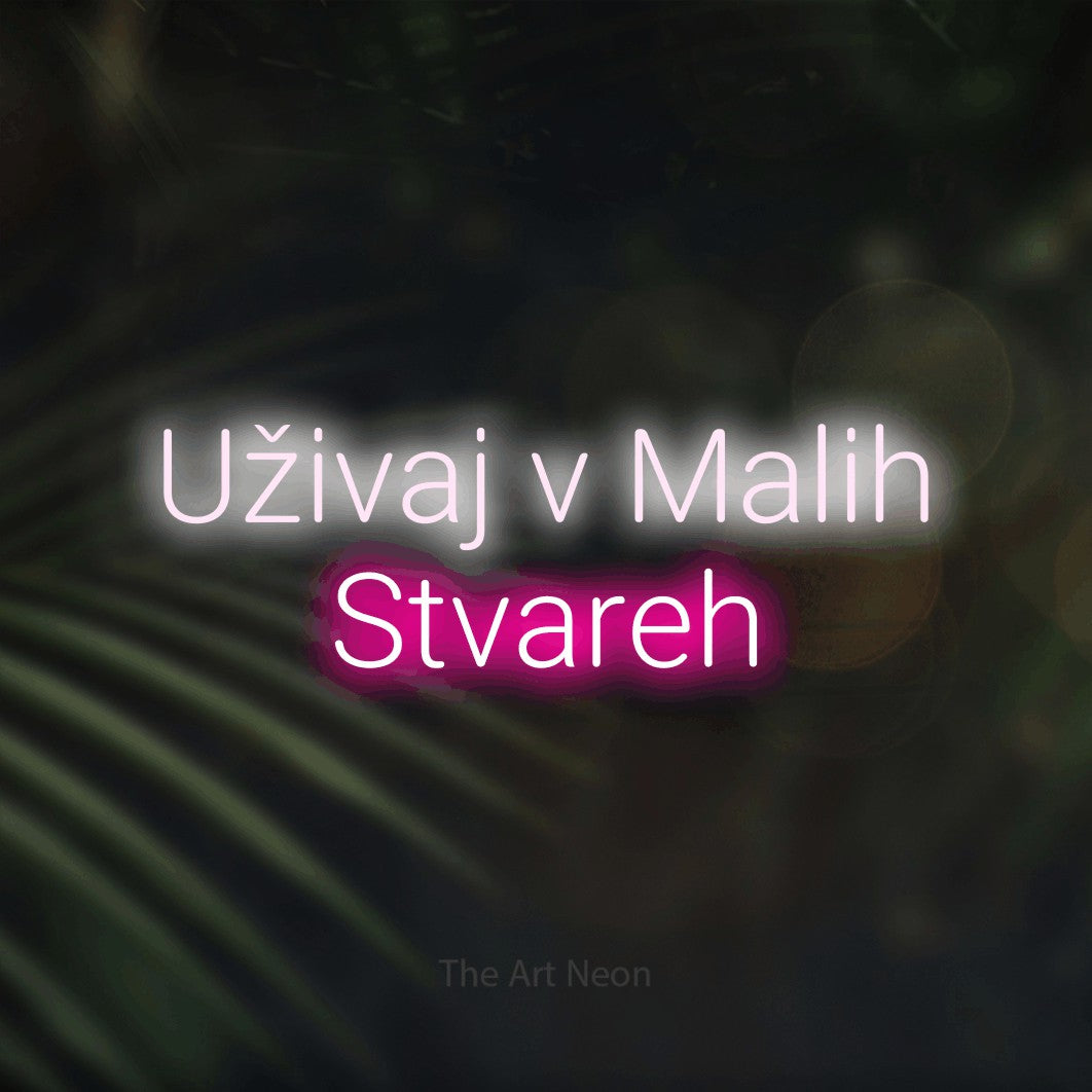 LED neon sign reading “Uživaj v Malih Stvareh”, arranged in two lines.