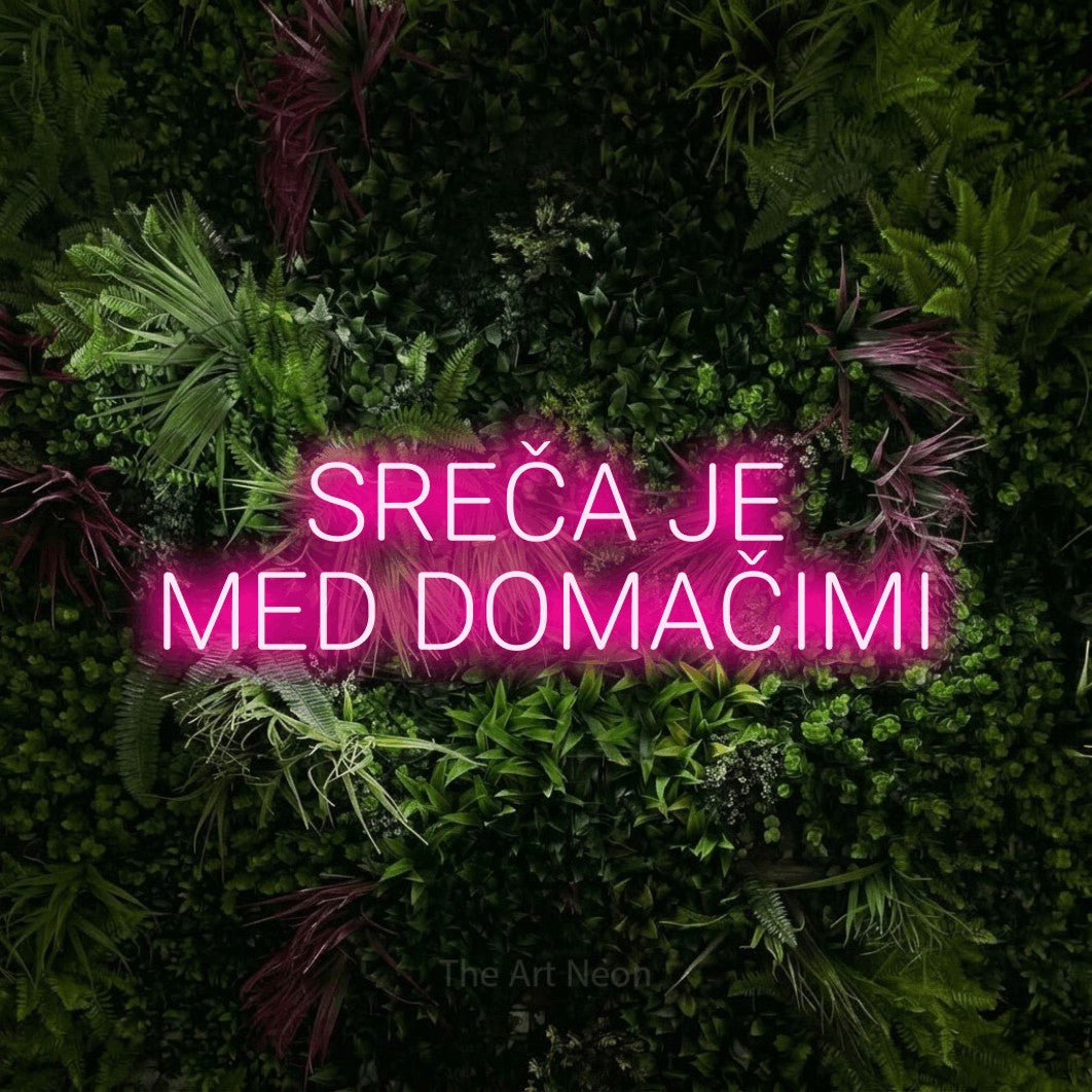 LED neon sign reading “SREČA JE MED DOMAČIMI”, arranged in two lines.