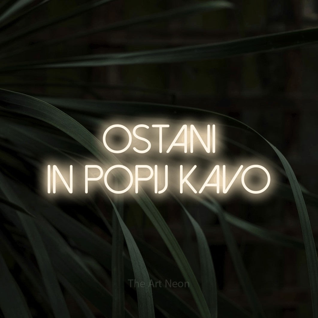 LED neon sign reading “Ostani in Popij Kavo”, arranged in two lines.