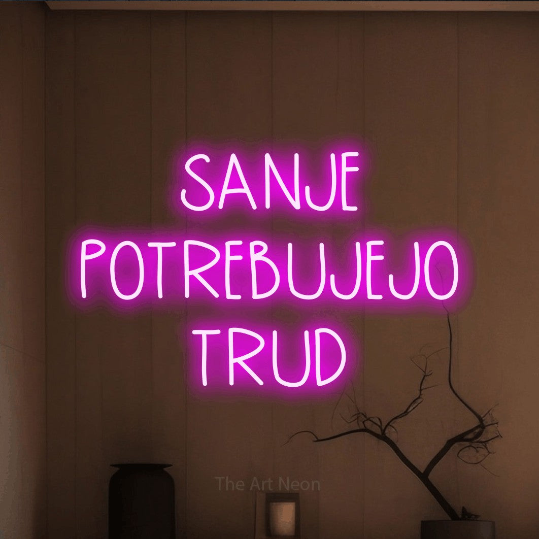 LED neon sign reading “SANJE POTREBUJEJO TRUD”, arranged in three lines.