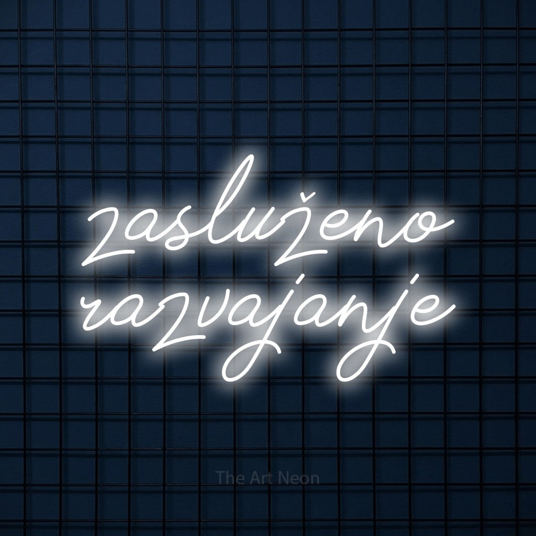 LED neon sign reading “zasluženo razvajanje”, arranged in two lines.