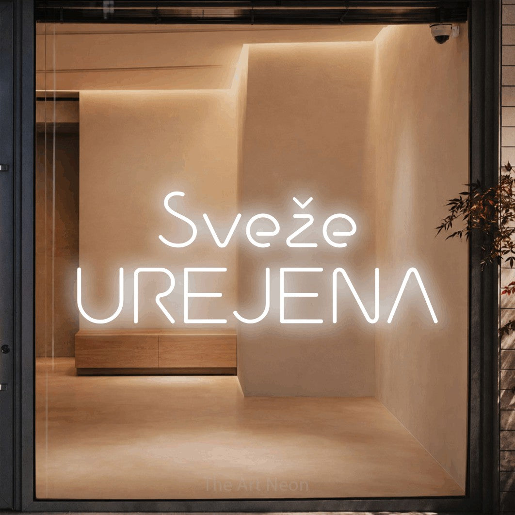 LED neon sign reading “Sveže UREJENA”, arranged in two lines.