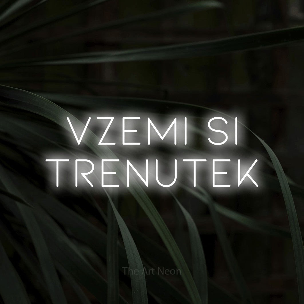 LED neon sign reading “Vzemi Si TRENUTEK”, arranged in two lines.