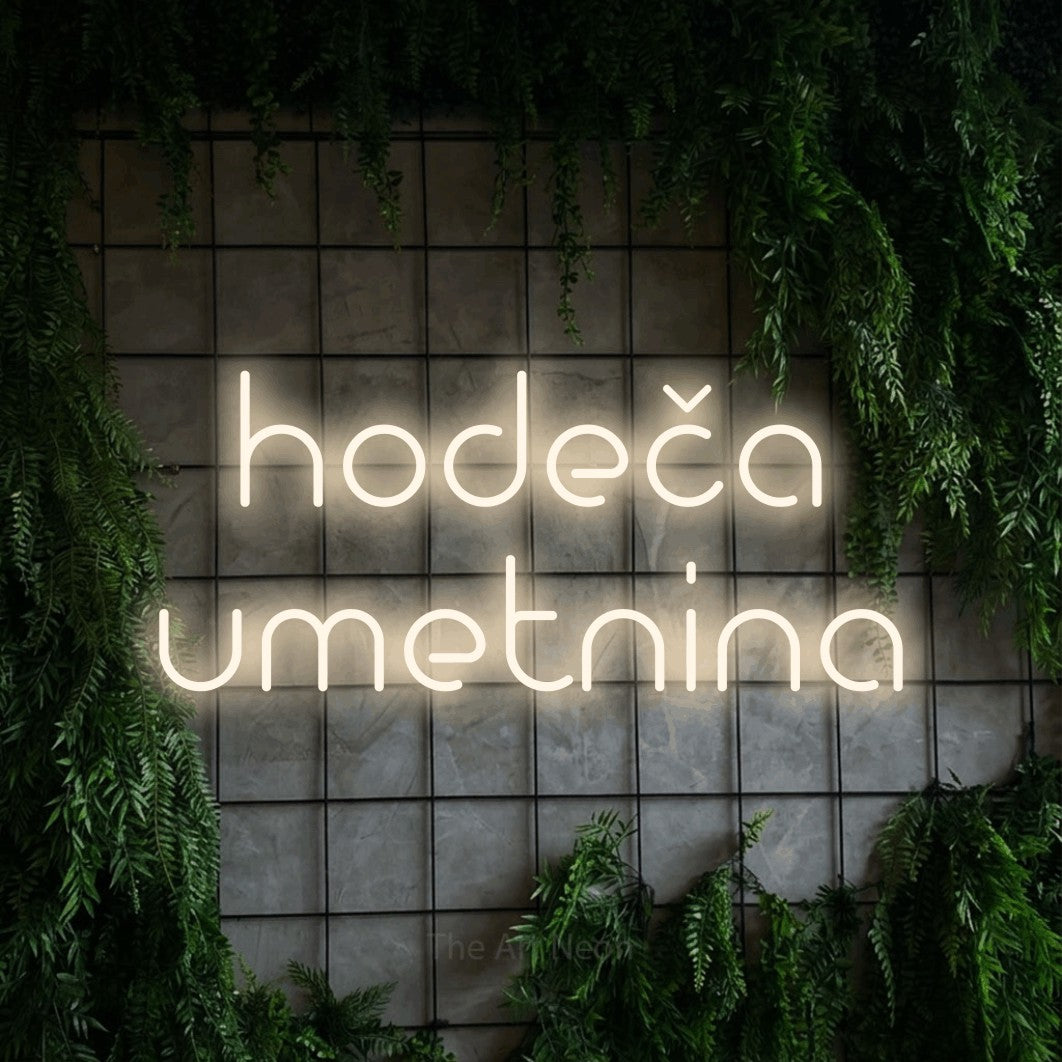 LED neon sign reading “hodeča umetnina”, arranged in two lines.