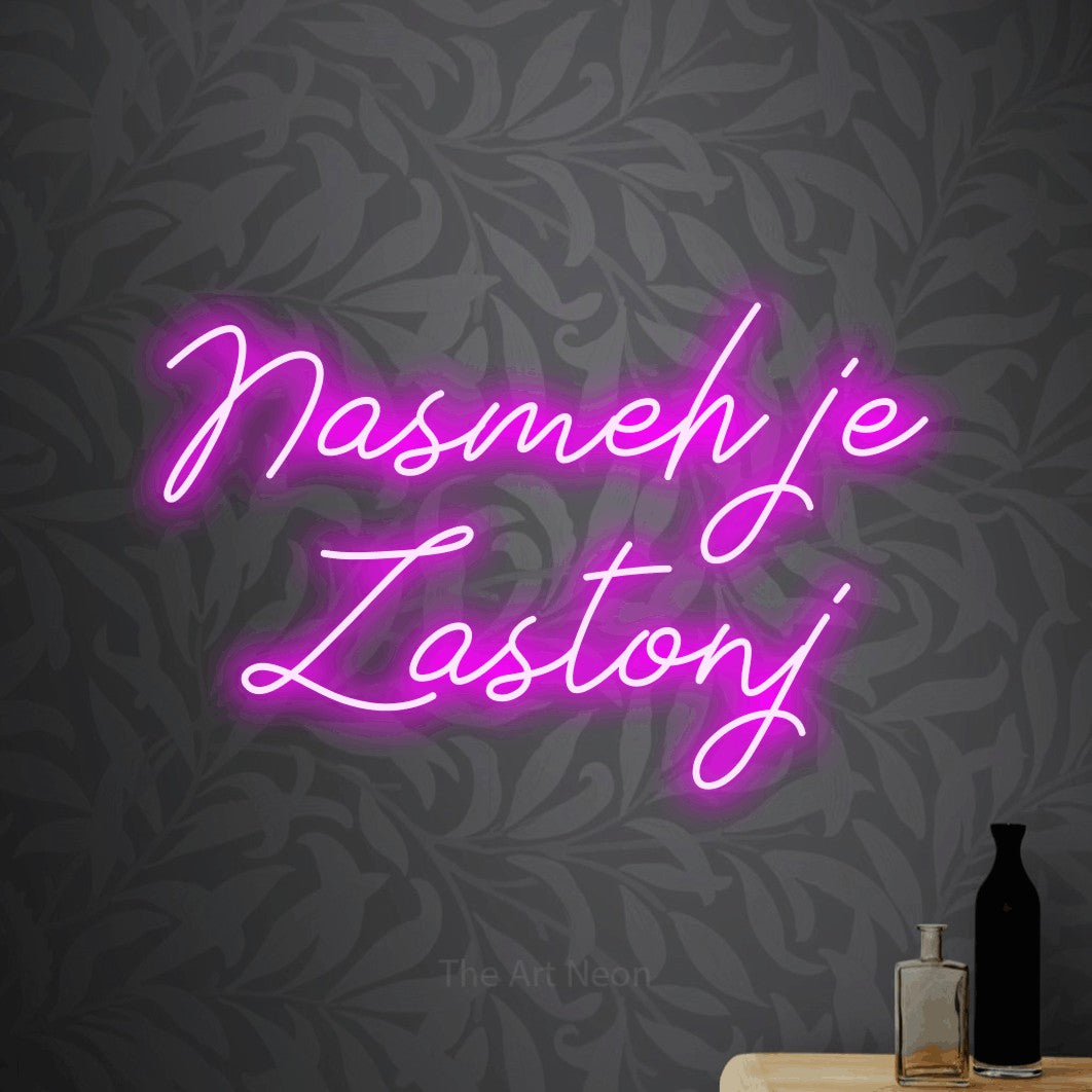 LED neon sign reading “Nasmeh je Zastonj”, arranged in two lines.