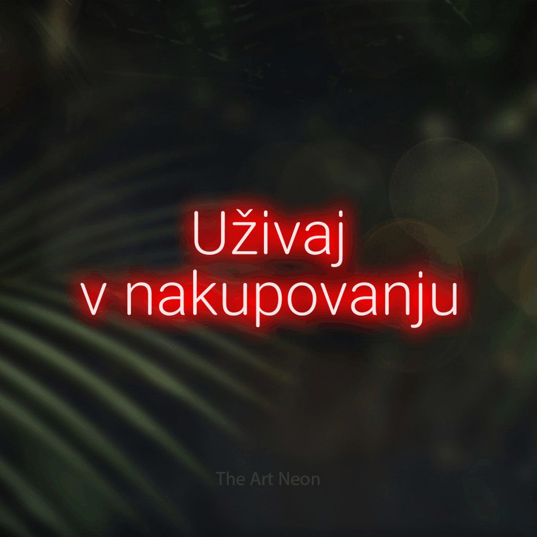 LED neon sign reading “Uživaj v nakupovanju”, arranged in two lines.