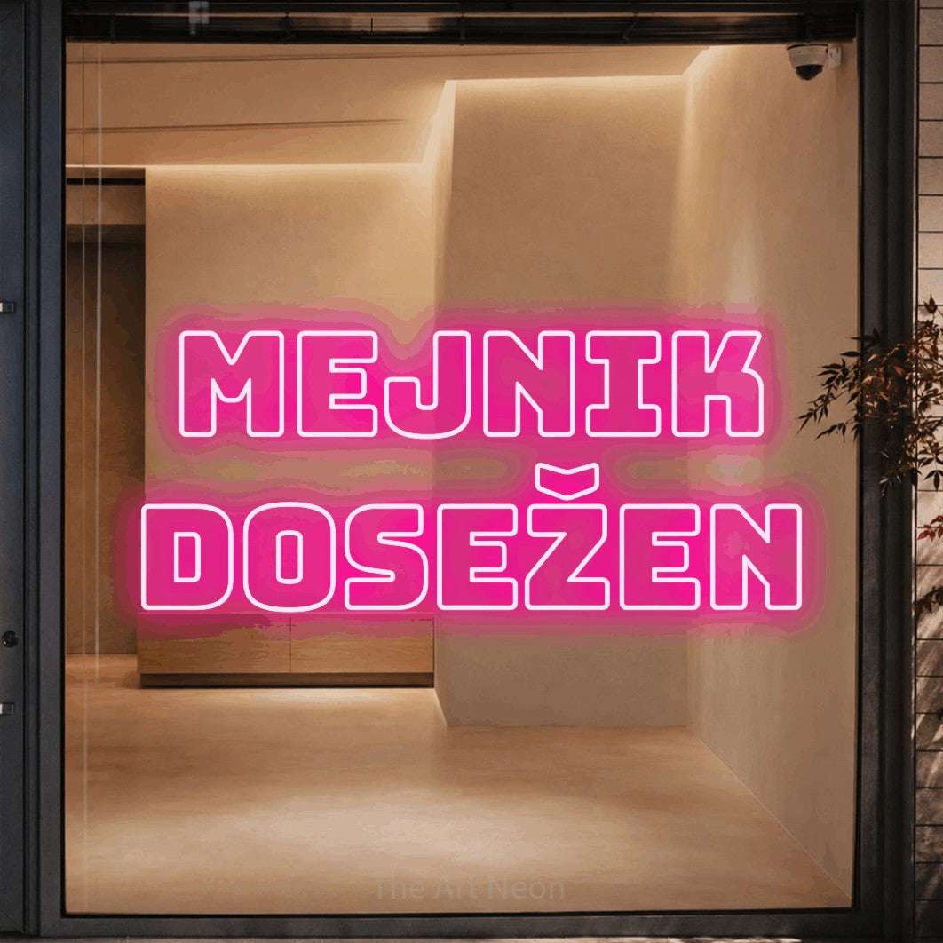 LED neon sign reading “mejnik dosežen”, arranged in two lines.