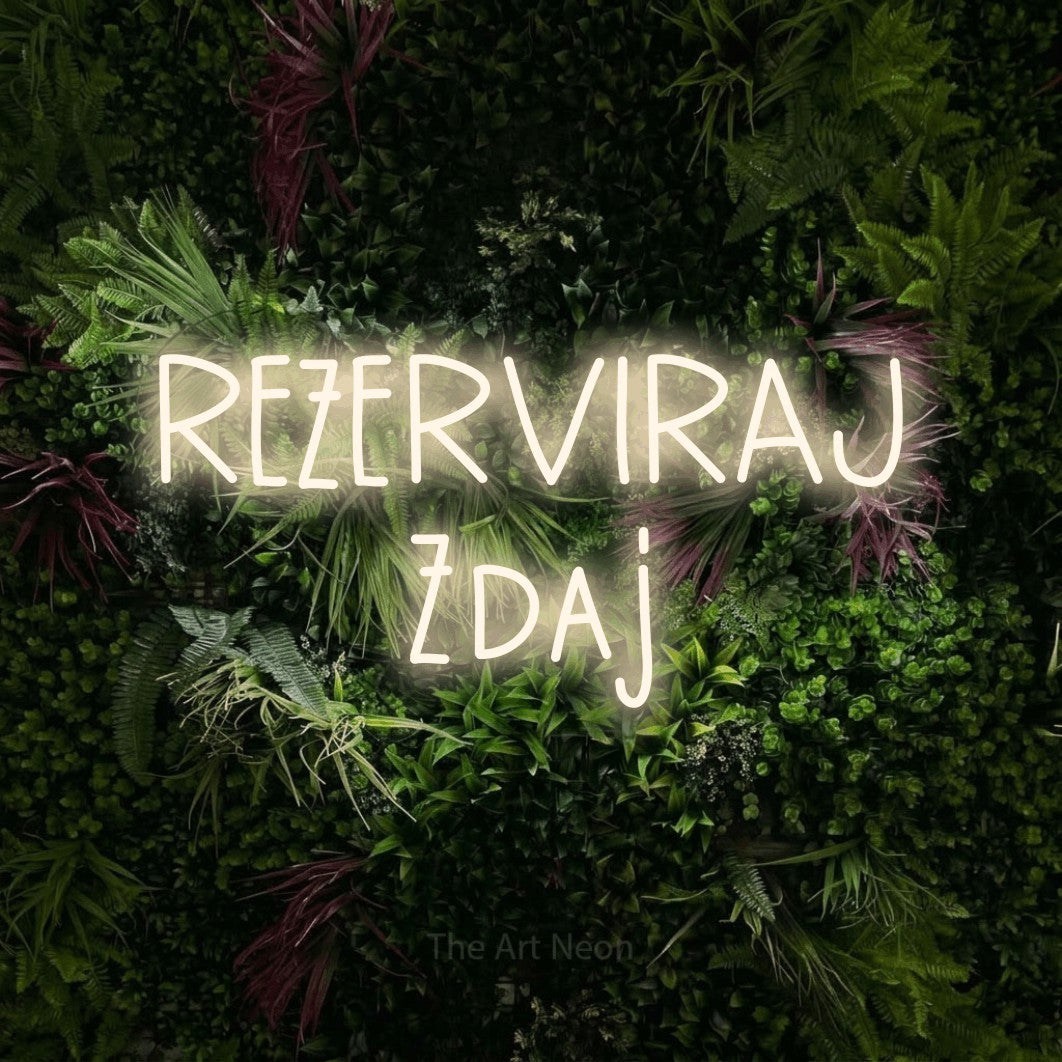 LED neon sign reading “REZERVIRAJ Zdaj”, arranged in two lines.