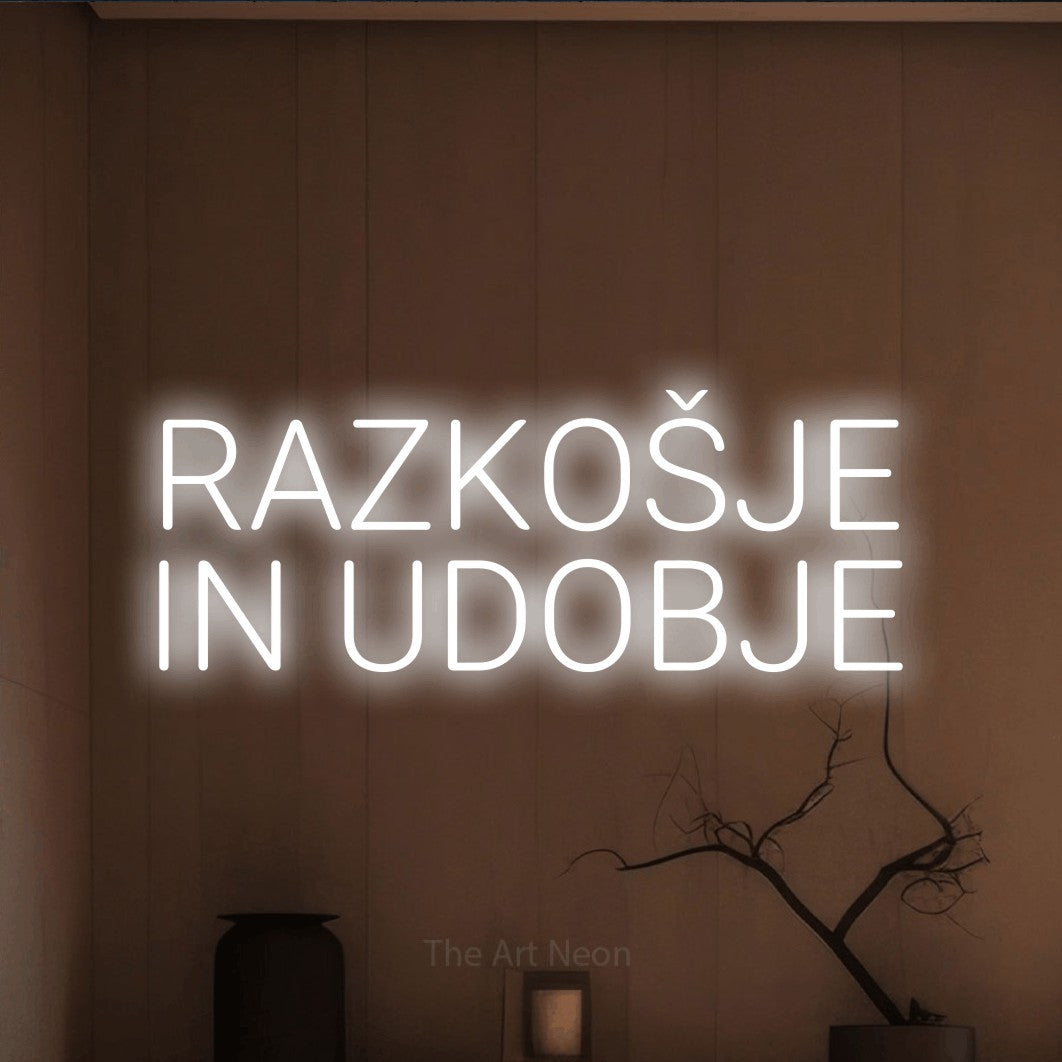 LED neon sign reading “RAZKOŠJE IN UDOBJE”, arranged in two lines.