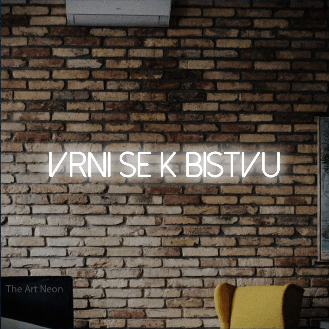 LED neon sign reading “Vrni se k Bistvu”, arranged in a single line.