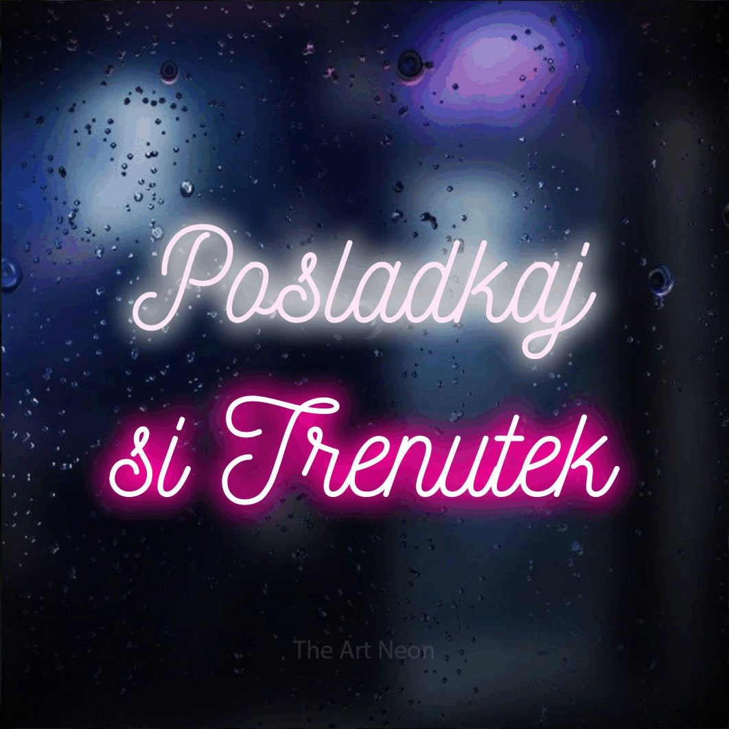LED neon sign reading “Posladkaj si Trenutek”, arranged in two lines.