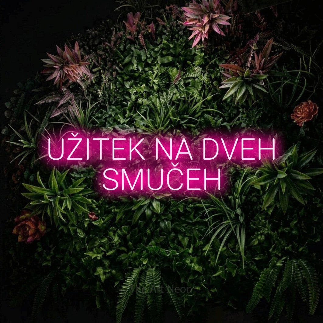 LED neon sign reading “UŽITEK NA DVEH SMUČEH”, arranged in two lines.