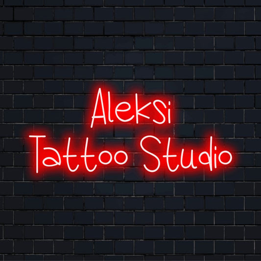 Aleksi Tattoo Studio Custom Name Neon Sign, bright neon glow against black brick wall