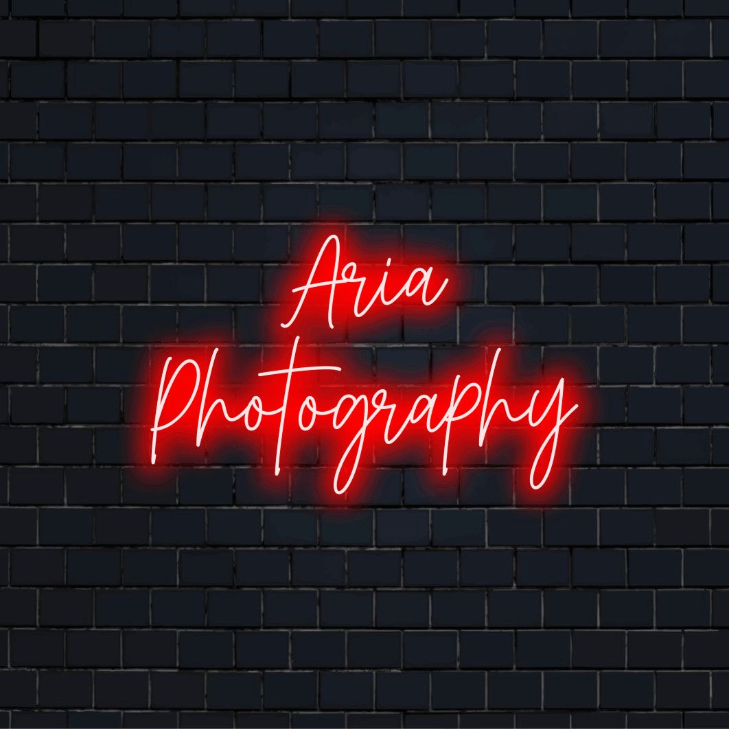 Aria Photography Custom Name Neon Sign, bright neon glow on black brick background