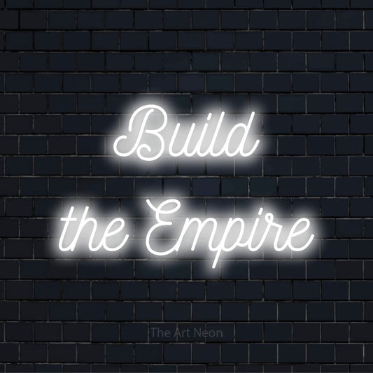 "Build The Empire" script-style LED neon sign on a black brick wall