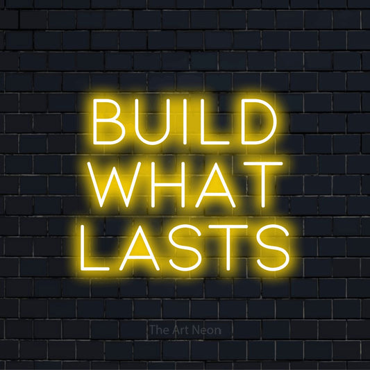 "Build What Lasts" text design with neon effect on a black brick wall